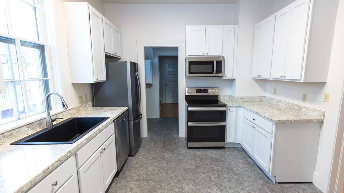 A white kitchen with an L-shaped counter and dining nook