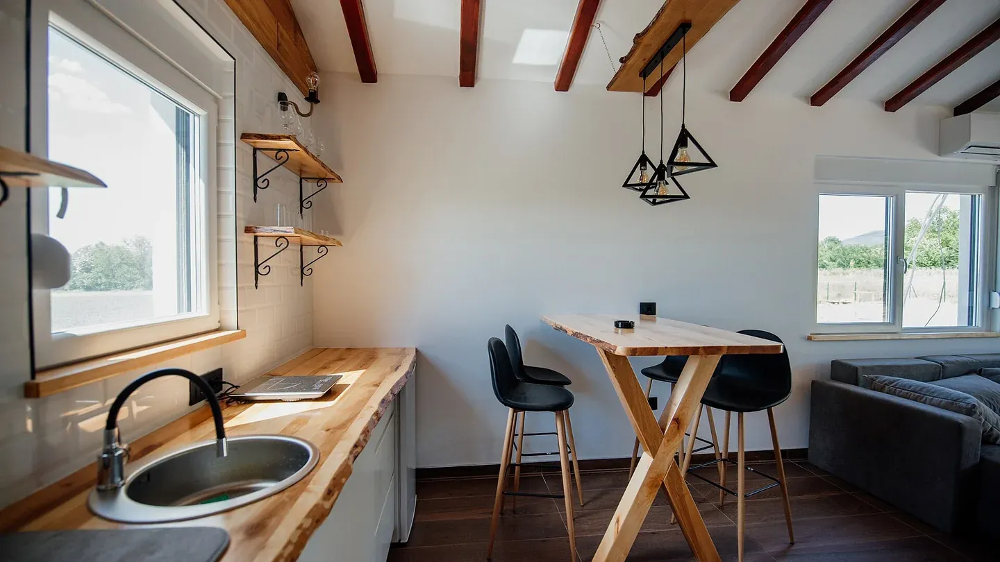 Japandi kitchen with a live-edge wood counter, no upper cabinets, and matte black pendants and chairs