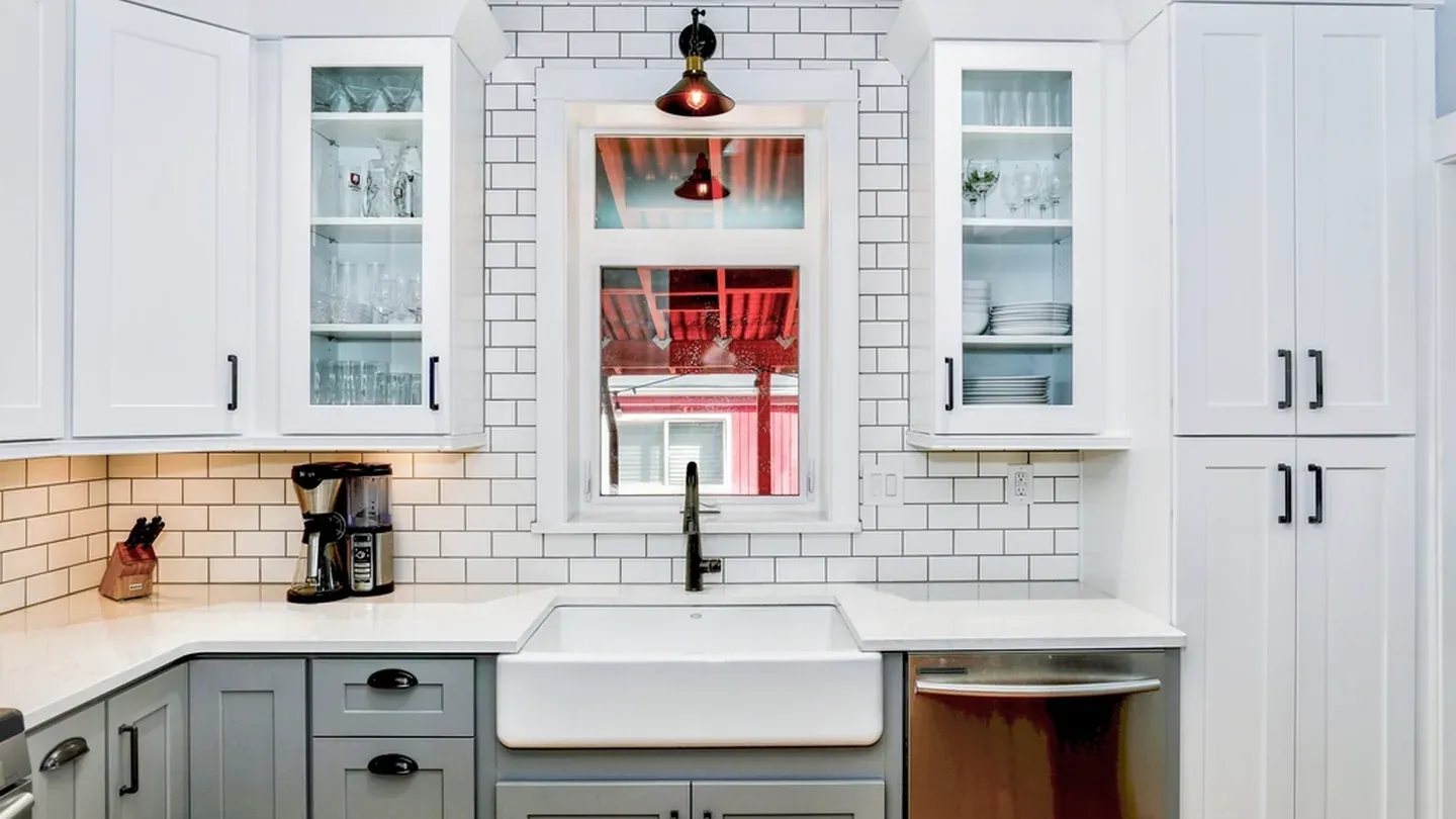 Transitional kitchen with white shaker doors, an apron-front sink and subway tile